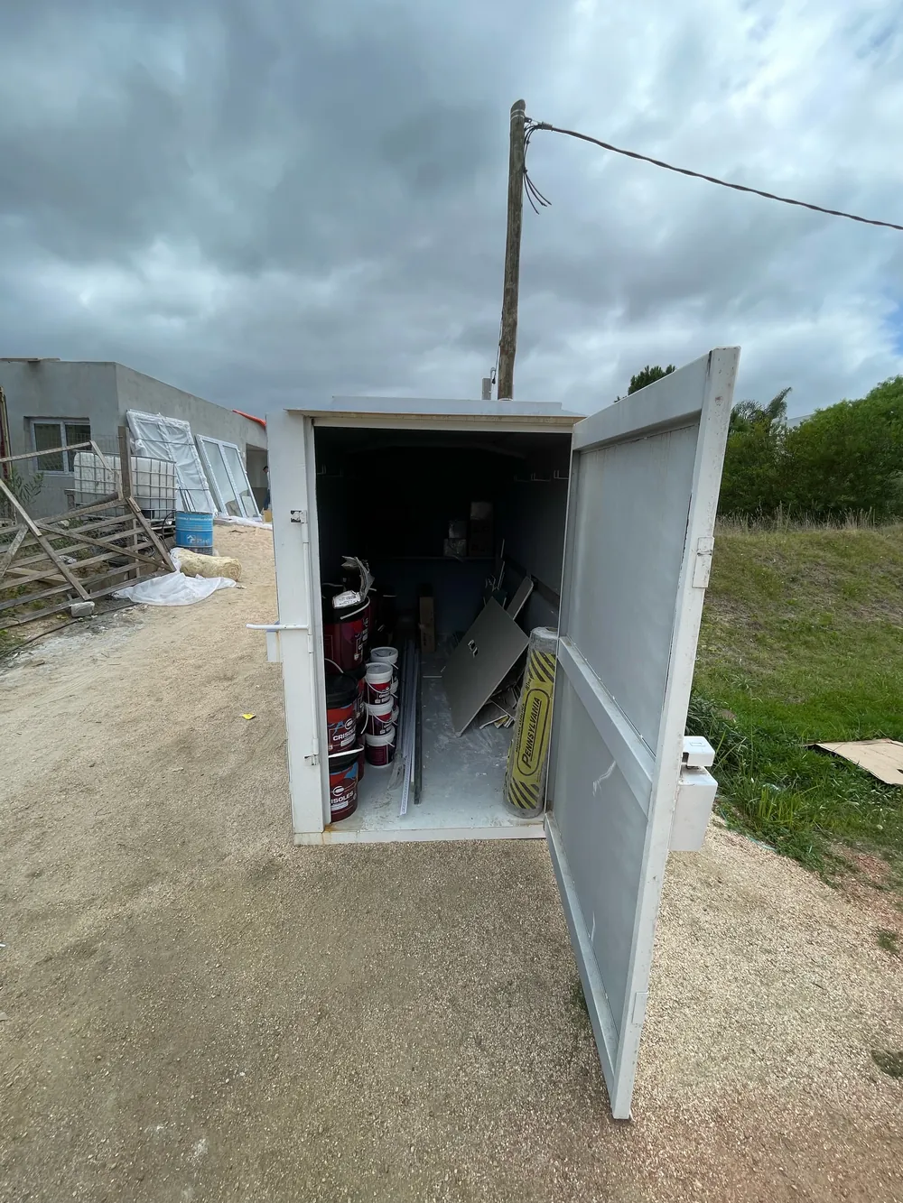 Obrador ObraBox con la puerta abierta y materiales de obra guardados adentro